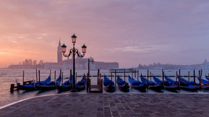 Gondolas docked in Venice at sunrise with San Giorgio Maggiore