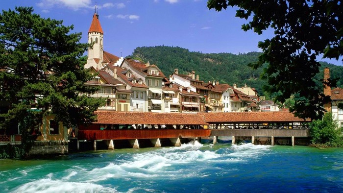 Town with covered bridge over river in Switzerland