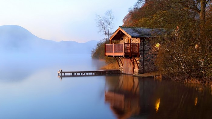 Stone boat house on a misty lake at dawn
