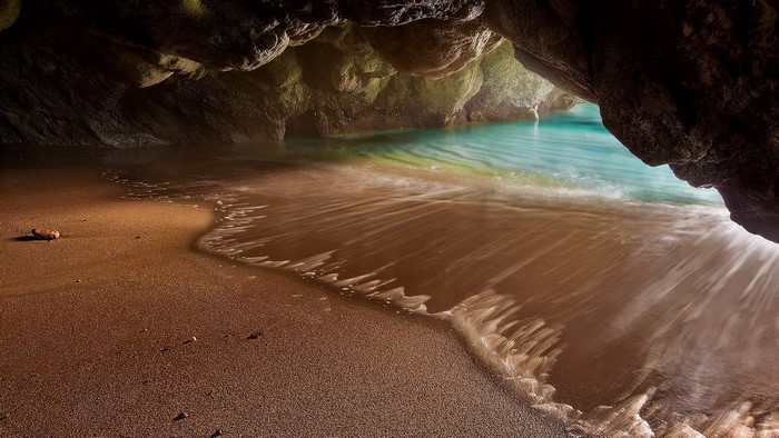 Sea cave with turquoise water and sandy beach
