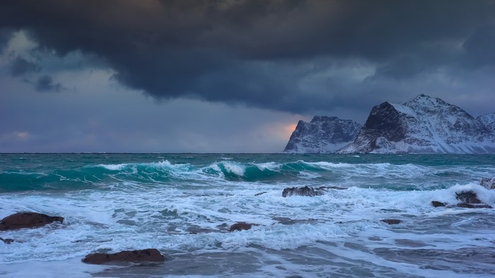 Rough Sea and Snow-Capped Mountains Under Stormy Sky