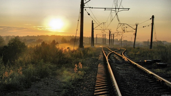 Railroad tracks at sunset with overhead wires