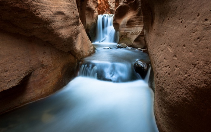 Waterfall flowing through a narrow sandstone canyon