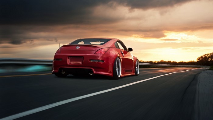 Red Nissan 350z driving on a road at sunset