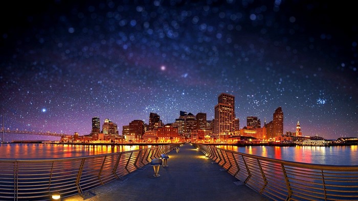 Cityscape at night with starry sky and bridge