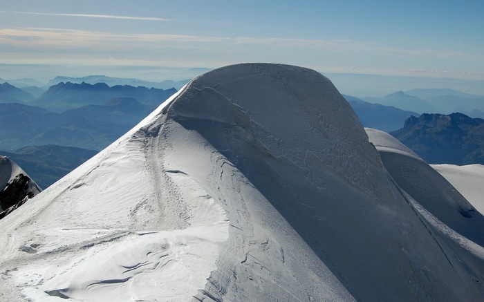 Snow-covered mountain peak with distant blue mountains