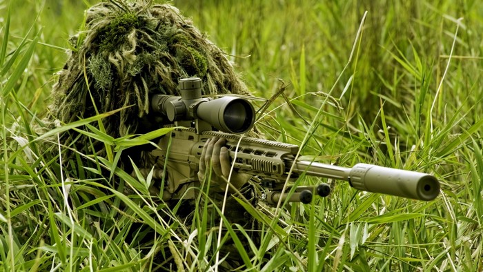 Military sniper in ghillie suit with rifle