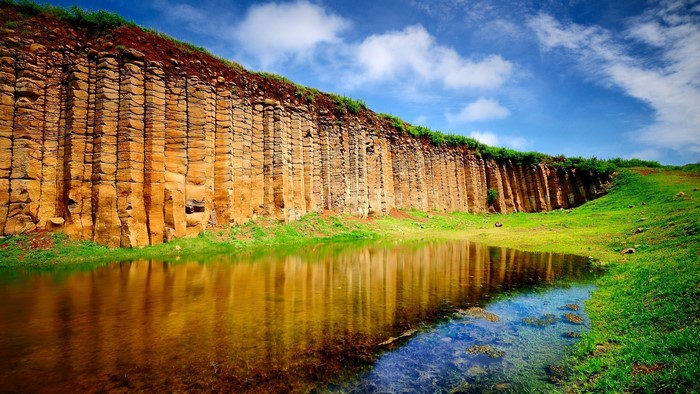 Unique basalt columns by a reflective pond