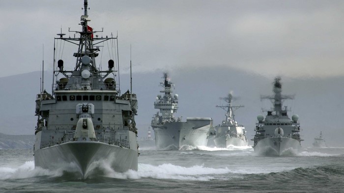 Navy ships sailing in formation on a cloudy day