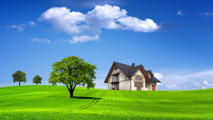 House on a green hill under a blue sky