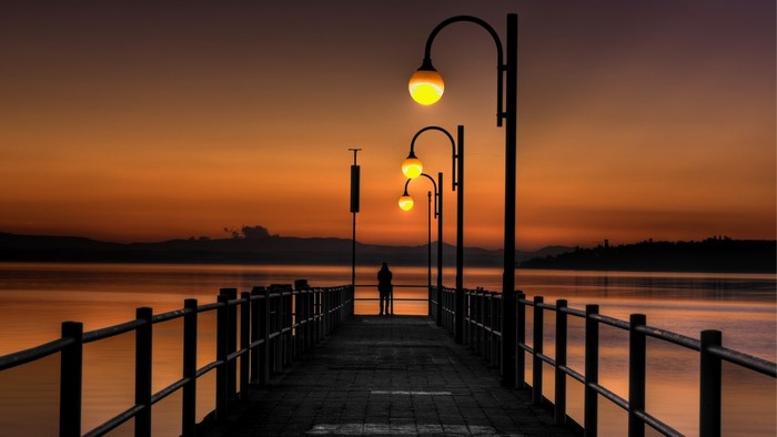 Pier with lamps at sunset over water