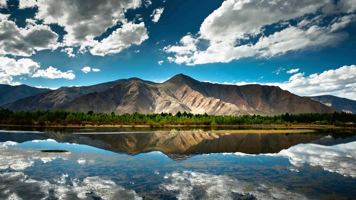 Mountain lake reflection with clouds and blue sky