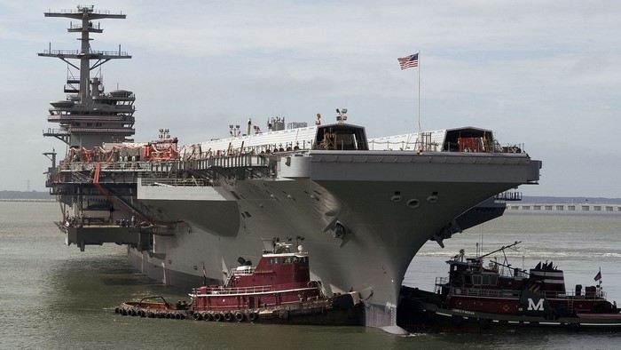 Aircraft carrier being assisted by tugboats