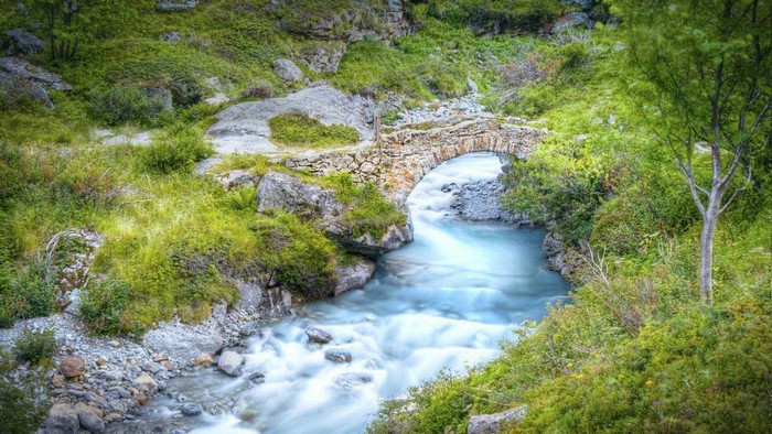 Stone bridge over a flowing river in a green landscape