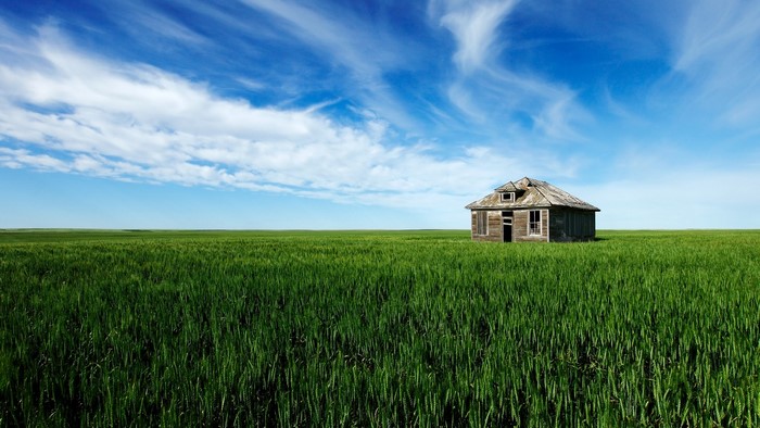 Old house in a green field under a blue sky