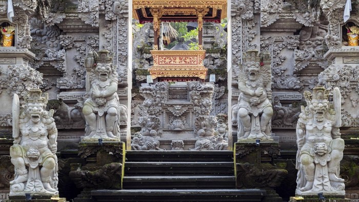 Stone statues guard entrance to Tjampuhan Temple in Bali
