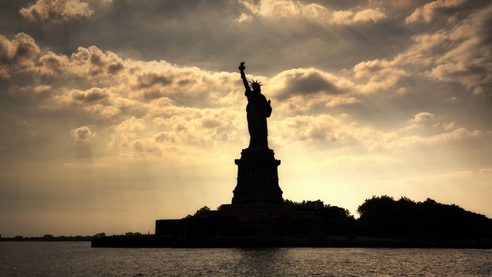 Statue of Liberty silhouetted against cloudy sky