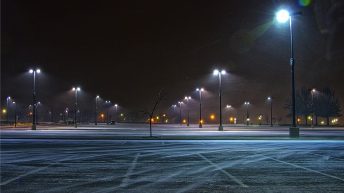 Snowy parking lot at night with streetlights