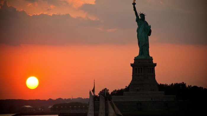 Statue of Liberty at sunset with sailboats