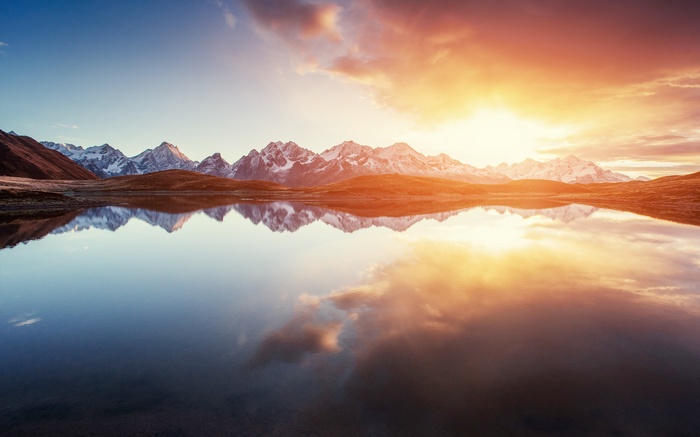Snow-capped mountains reflected in a lake at sunrise