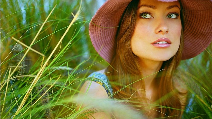 Olivia Wilde in a pink hat among tall grass