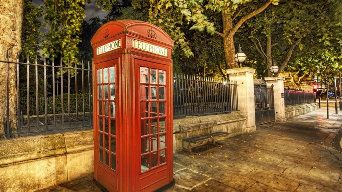 Red British Telephone Booth on a Street at Night
