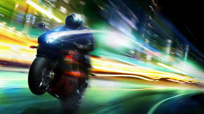 Motorcyclist performing a wheelie at night