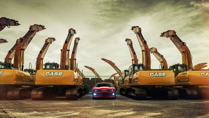 Red Chevrolet Camaro parked between Case excavators