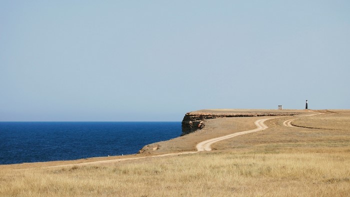 Dirt road leading to a lighthouse on a cliff by the sea