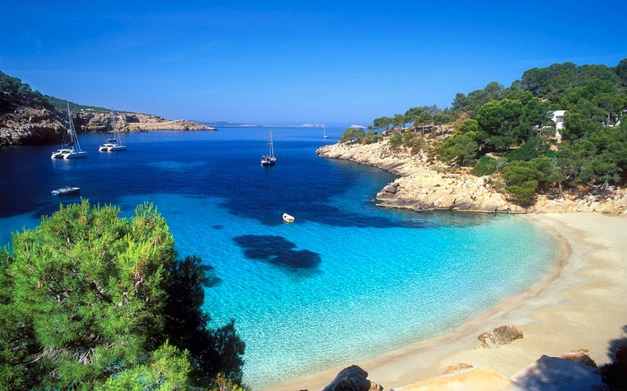 Boats in a tropical bay with a sandy beach