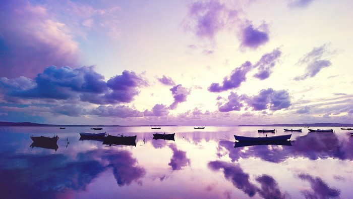 Purple sunset over ocean with boats
