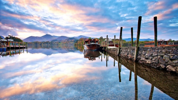 Boats docked on a lake with mountain reflections