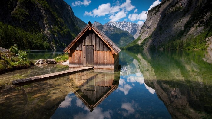 Wooden cabin on a lake with mountains