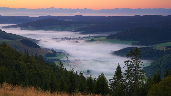 Foggy valley at sunrise with distant mountains