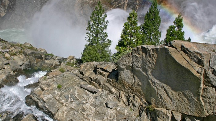 Rainbow over a waterfall and rocky cliff