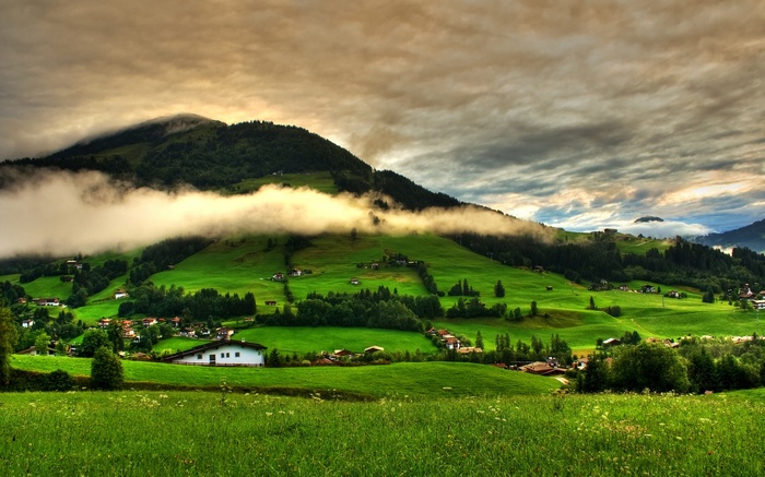 Green rolling hills with houses and clouds