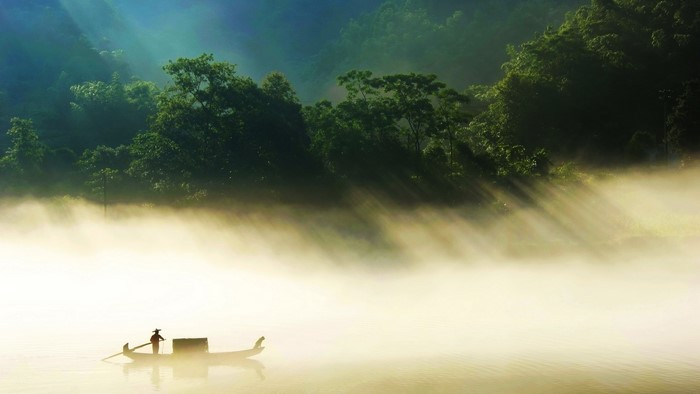 Fisherman on a boat in misty countryside