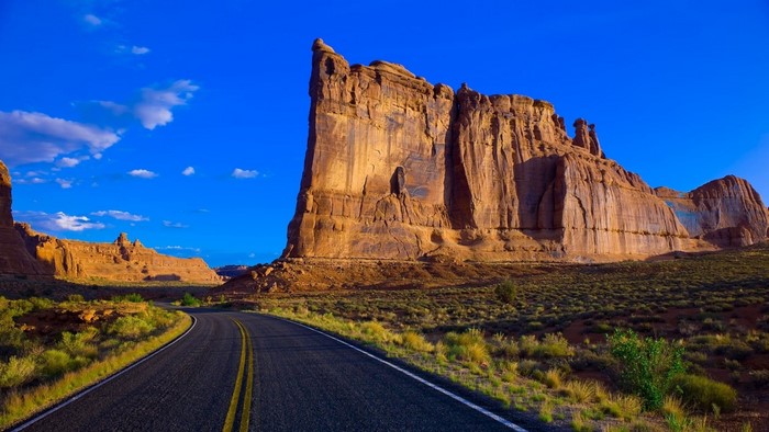 Road through Monument Valley under a blue sky