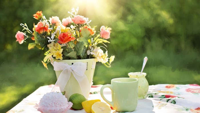 Summer flowers in a pot with tea set on a table