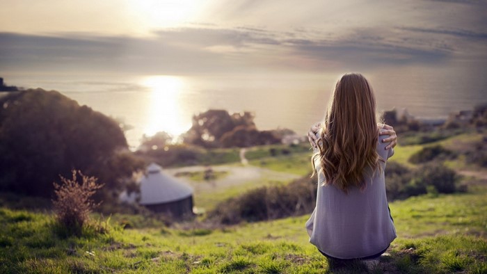 Girl hugging herself looking at the ocean