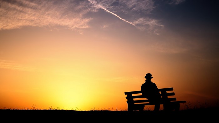 Silhouette of a person on a bench at sunset