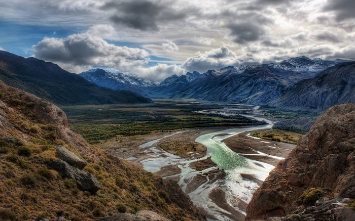 Winding River Valley Between Mountains Under Cloudy Sky