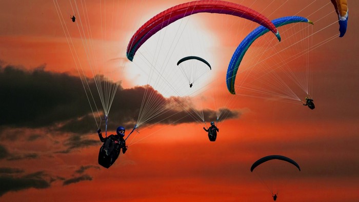 Paragliders flying against a sunset sky