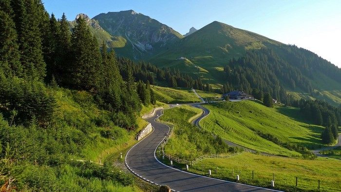 Winding mountain road through green hills and forests in Switzerland