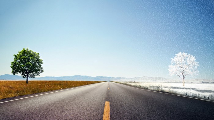 Road dividing summer and winter landscapes