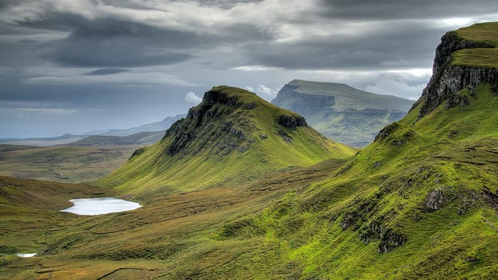 Green rolling hills and mountains under cloudy sky