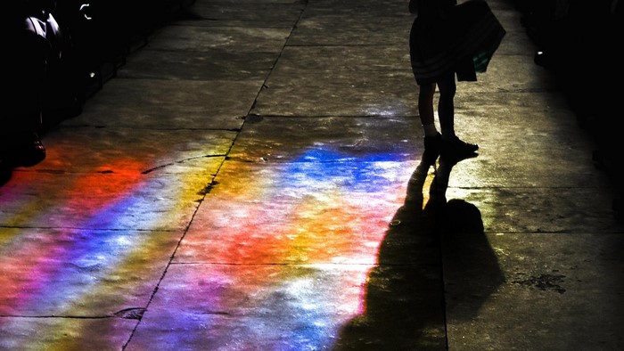 Person walking on a path with colorful light reflections