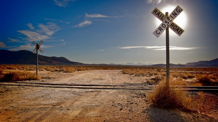 Desert Railroad Crossing with Sun