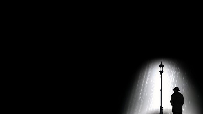 Silhouette of a man under a streetlight in the rain