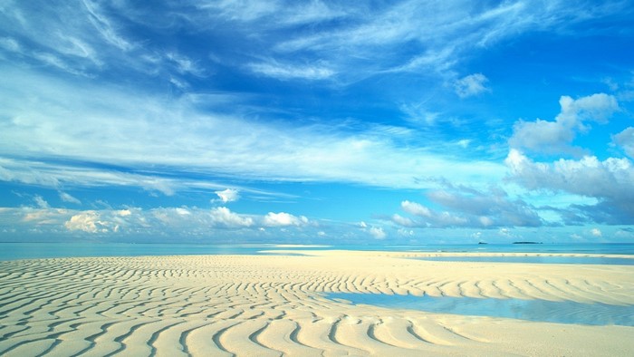 Sandy beach with rippled sand and blue sky
